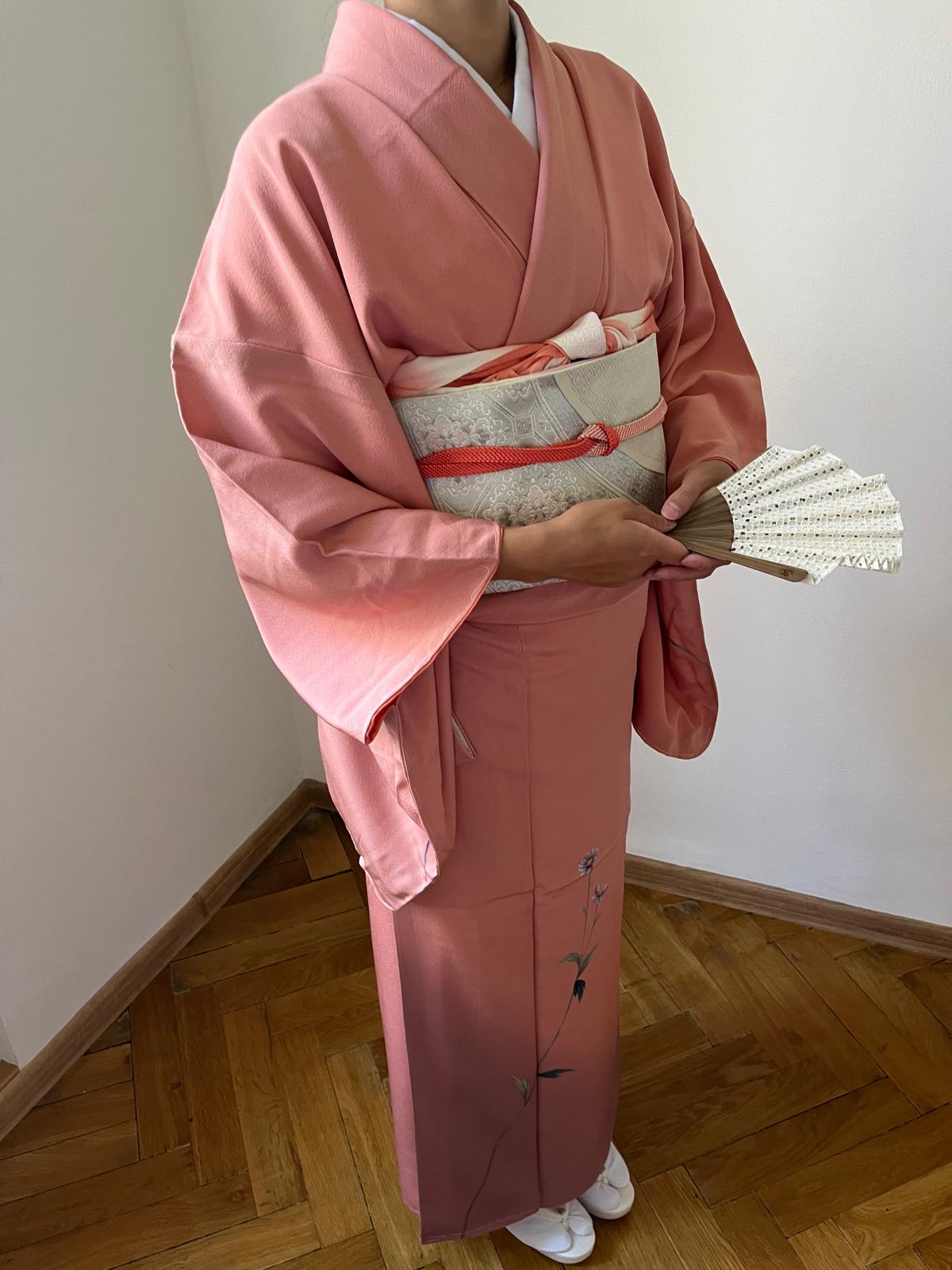 Woman wearing a pink kimono and holding a folding fan