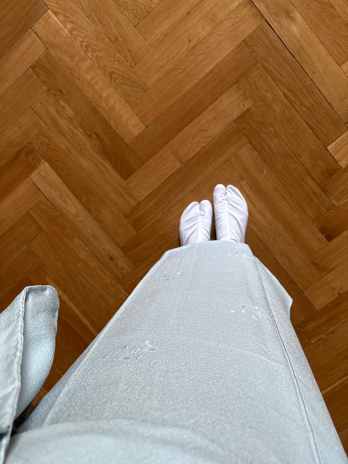 View of a pale kimono and white tabi socks on a parquet floor